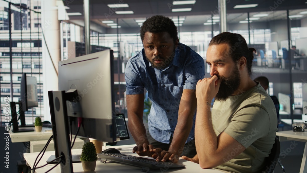 Poster employee using computer to analyze datasets, being assisted by helpful coworker on comparing account