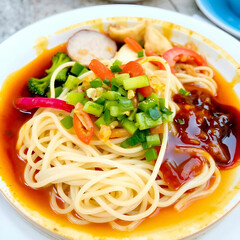 Steaming Plate of Noodles Garnished with Fresh Veggies and Sauces