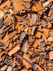 Colored mulch chips in vibrant orange and brown hues, used for landscaping and gardening