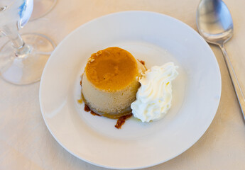 Delicate flan dessert is custard creamy delicacy made from milk, eggs and sugar. Dish is decorated with whipped cream