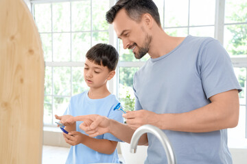 Happy father and his little son with razors near mirror in bathroom