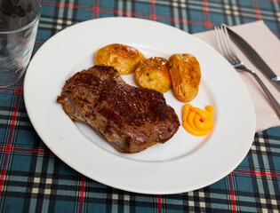Portion of just cooked grilled beef steak with roasted potatoes.