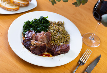 Appetizing hot beef in sauce served with spinach and lentils on platter..