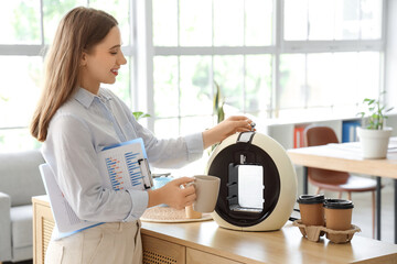 Young businesswoman making coffee in office