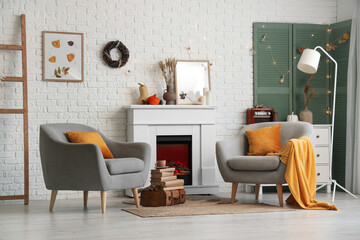 Armchairs, fireplace and autumn decor in interior of living room
