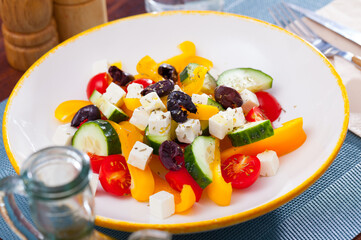 Traditional Greek salad with fresh vegetables, feta cheese and black olives served on white plate