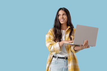 Obraz premium Portrait of pretty young woman with laptop on blue background