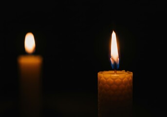 A close-up showcases two lit candles against a black background, evoking a warm and calming atmosphere.