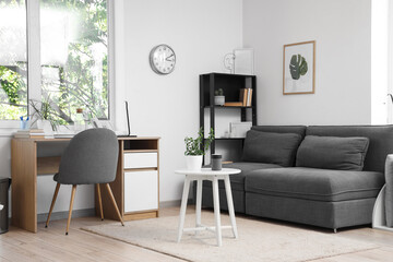 Interior of living room with modern grey sofa, coffee table and workspace