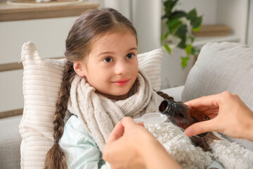 Sick little girl with her mother pouring cough syrup at home, closeup
