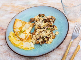 Tasty scrambled eggs with asparagus, mushrooms and pancakes