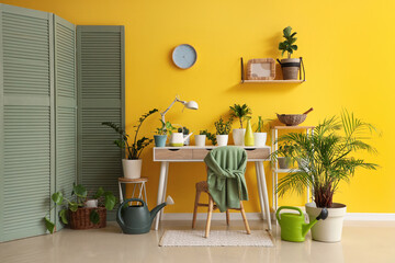 Interior of room with green plants, table and folding screen