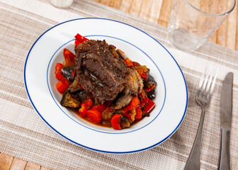 Baked pork chop with vegetable garnish of sauteed bell pepper, tomatoes, eggplant and onions. Tasty homemade dinner
