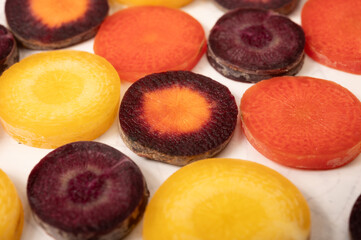 Colorful fresh raw purple, yellow, red and purple-orange carrots roots vegetables from greenhouse...