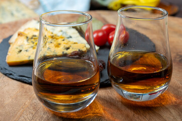 Whiskey and cheese pairing, tasting whisky glasses and plate with sliced crumbly old blue stilton and blue shropshire cheeses, Great Britain food and drink