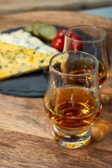 Whiskey and cheese pairing, tasting whisky glasses and plate with sliced crumbly old blue stilton and blue shropshire cheeses, Great Britain food and drink