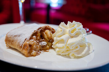Austrian desserts, piece of apple strudel with whipped cream served in traditional bakery cafe in Vienna, close up