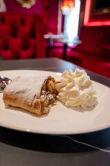 Austrian desserts, piece of apple strudel with whipped cream served in traditional bakery cafe in Vienna, close up