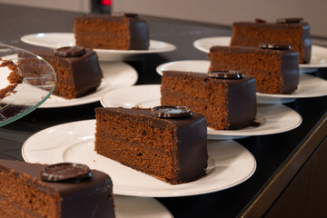 Many white plates with pieces of famous Sachertorte chocolate cake with apricot jam of Austrian...
