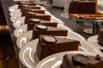 Many white plates with pieces of famous Sachertorte chocolate cake with apricot jam of Austrian...