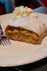 Austrian desserts, piece of apple strudel with whipped cream served in old traditional bakery cafe in Vienna, close up