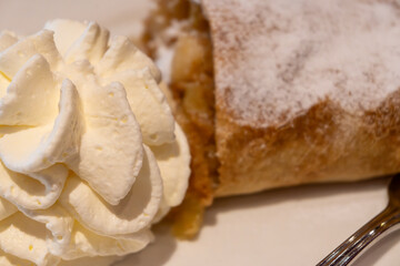 Austrian desserts, piece of apple strudel with whipped cream served in old traditional bakery cafe in Vienna, close up