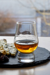 Whiskey and cheese pairing, tasting whisky glass and plate with sliced blue stilton and blue shropshire cheeses, Great Britain food and drink