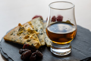 Whiskey and cheese pairing, tasting whisky glass and plate with sliced blue stilton and blue shropshire cheeses, Great Britain food and drink