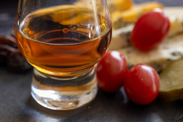 Whiskey and cheese pairing, tasting whisky glasses and plate with sliced crumbly old blue stilton and blue shropshire cheeses, Great Britain food and drink