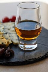 Whiskey and cheese pairing, tasting whisky glass and plate with sliced blue stilton and blue shropshire cheeses, Great Britain food and drink