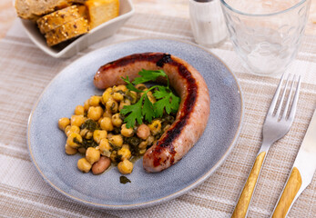 Delicious lunch from sausages, chickpeas with spinach on table