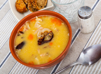 Appetizing hot pea soup with smoked meats served with slices of bread