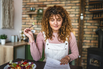 adult curly hair woman eat fresh salad while work remotely at home