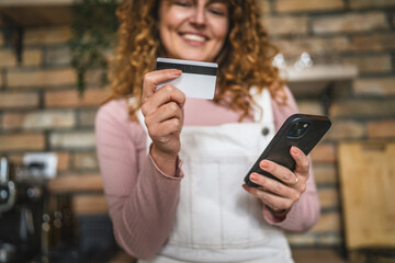 woman use mobile phone and credit card for online purchase at kitchen