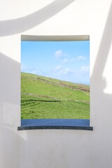 Framed Panoramic View Through Architectural Window to Lush Mountain Landscapes. Breathtaking Perspective of Terceira Island Verdant Patchwork Fields Seen Through Traditional Azorean Building Window