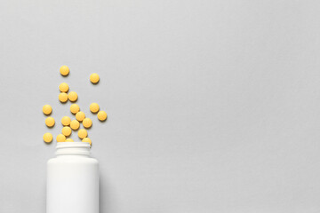 Jar with yellow pills on grey background