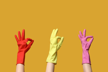 Female hands in rubber gloves showing OK on yellow background