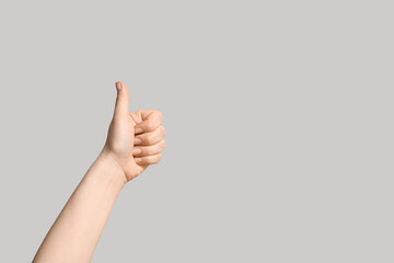 Female hand showing thumb-up on light background