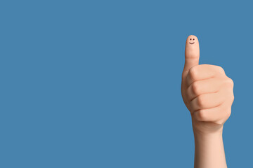 Female hand showing thumb-up on blue background