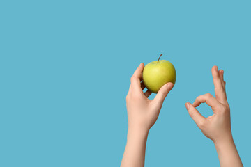 Female hands with apple showing OK on blue background