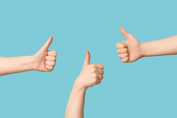 Female hands showing thumbs-up on blue background