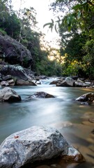 Obraz premium A tranquil river gliding between rugged rocks with a silky smooth flow under a misty atmosphere