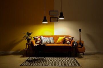 Interior of dark living room with sofa, guitar and glowing lamps