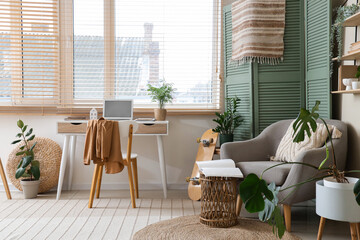 Interior of room with comfortable workplace, folding screen and armchair