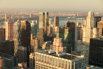 Aerial view of Manhattan skyscrapers illuminated by warm sunset light with the Hudson River in the background, New York City, USA