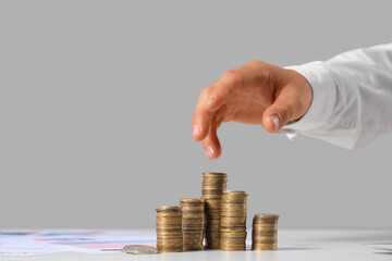 Businessman's hand counting coins on table against grey background