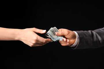 Businessman giving money to woman on black background, closeup