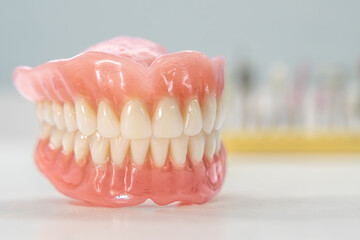 Close-up of a dental prosthetic model with artificial teeth and gums on a wooden surface. Ideal for dental care imagery