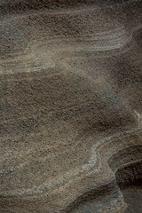 Rough textured brown rock surface forming wavy pattern