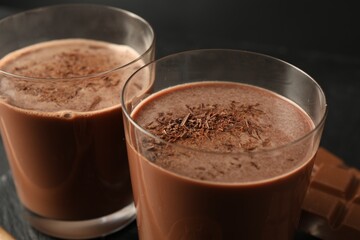 Tasty chocolate milk with shavings on black table, closeup
